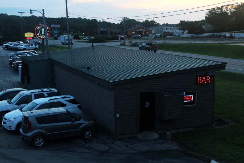 A graphic of the side of the Annex building. Neon signs that read "Bar" and "Open" can be seen.