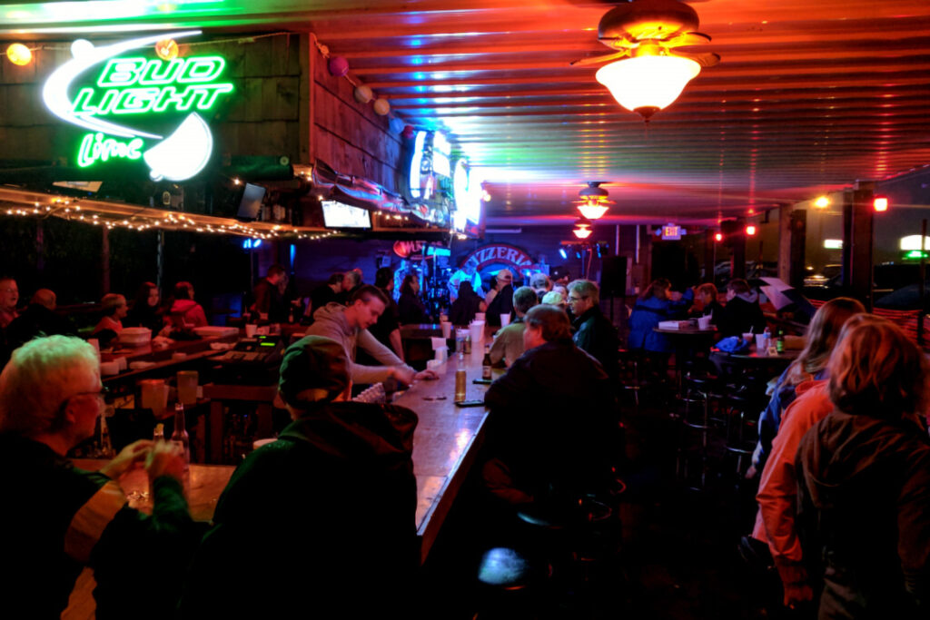 A graphic of the colorful neon lights lighting up a busy Back Bar at night