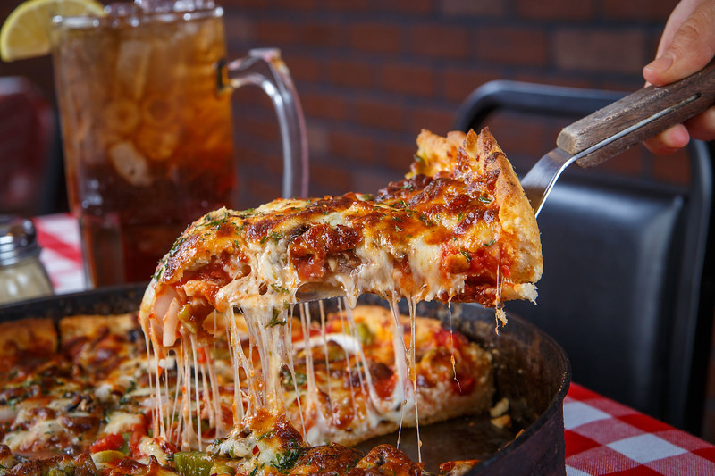 A graphic of a slice of deep dish pizza being lifted from the pan.