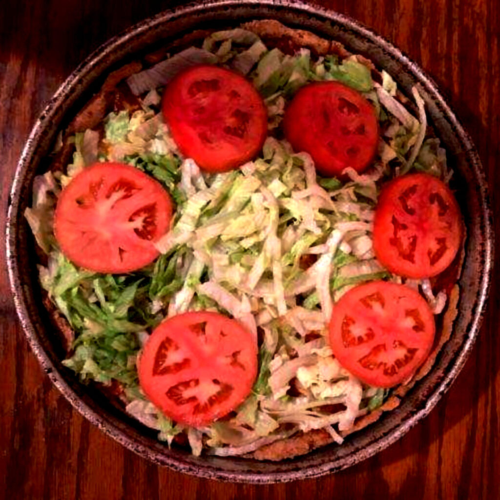 A graphic of a deep dish BLT pizza topped with shredded lettuce and tomato slices.